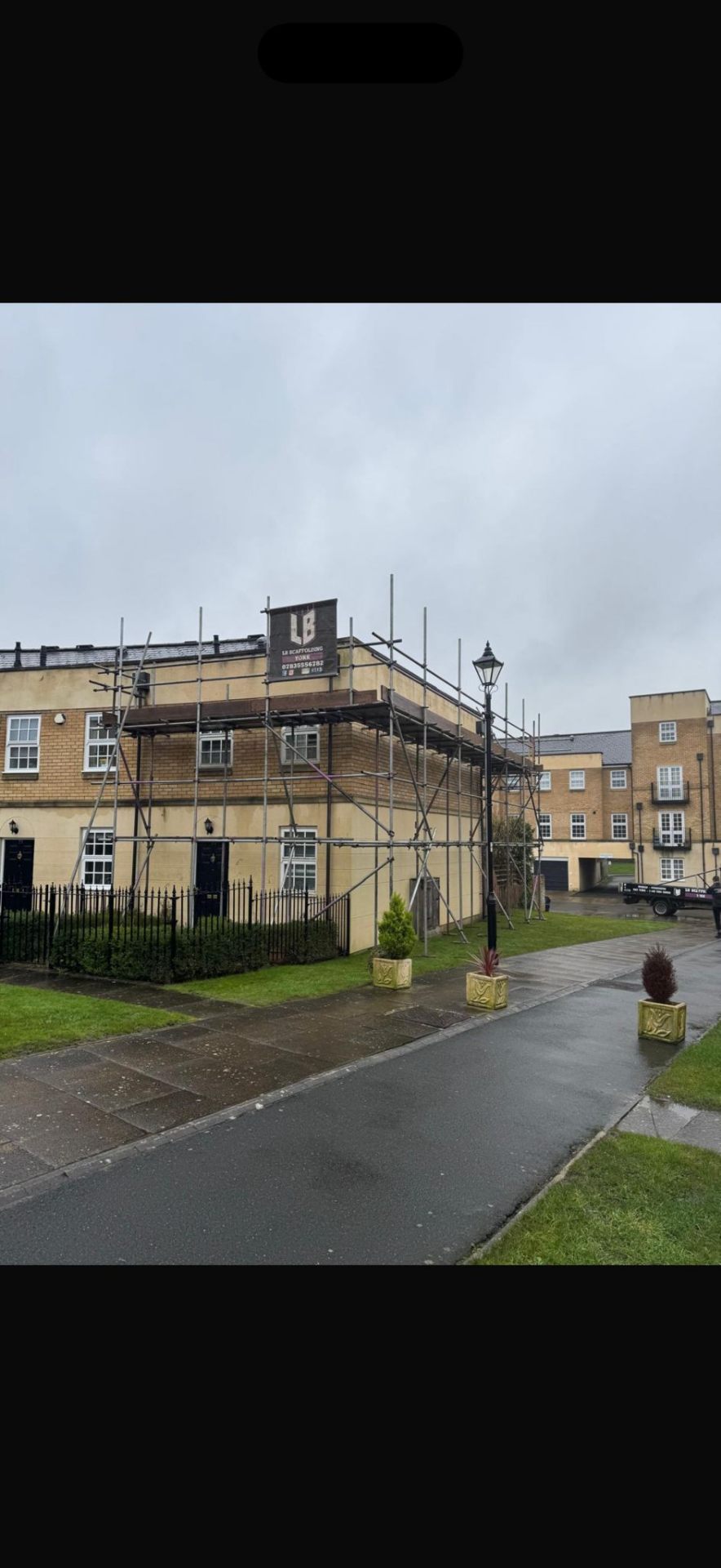 Stone-fronted townhouse with rear scaffolding and LB Scaffolding Ltd branded banner