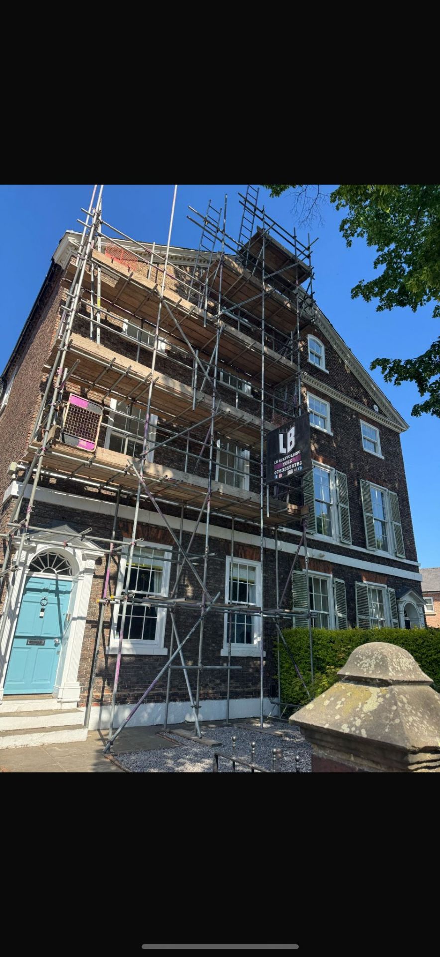 Tall Georgian brick townhouse with multi-lift scaffolding for sash window restoration