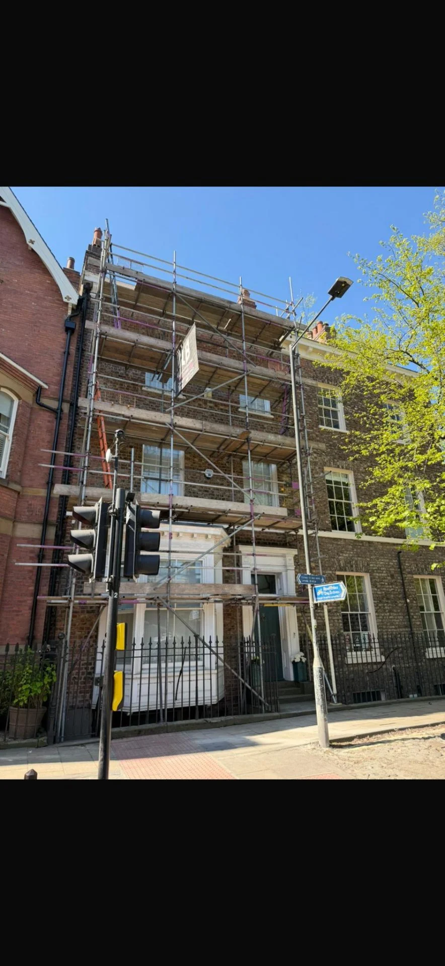 Tall brick townhouse with full-height scaffolding and LB Scaffolding Ltd banner on the front elevation