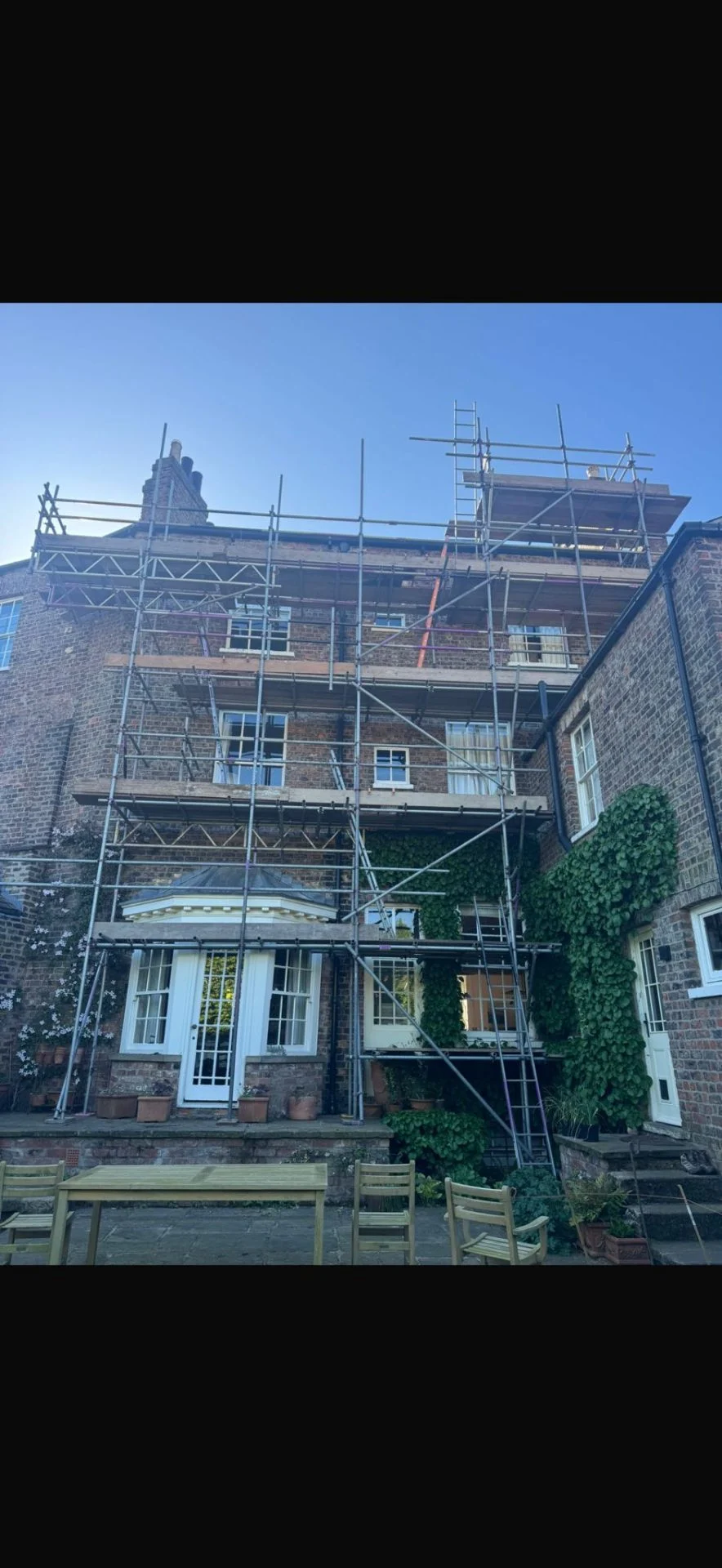 Rear of a large York period property with full perimeter scaffolding above a paved garden