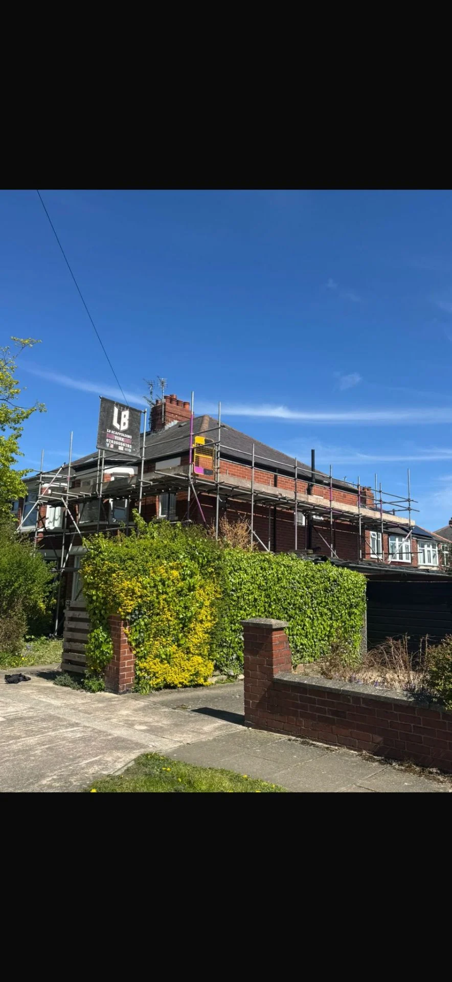 Yorkshire semi-detached home with rear roof-line scaffolding and LB Scaffolding Ltd banner