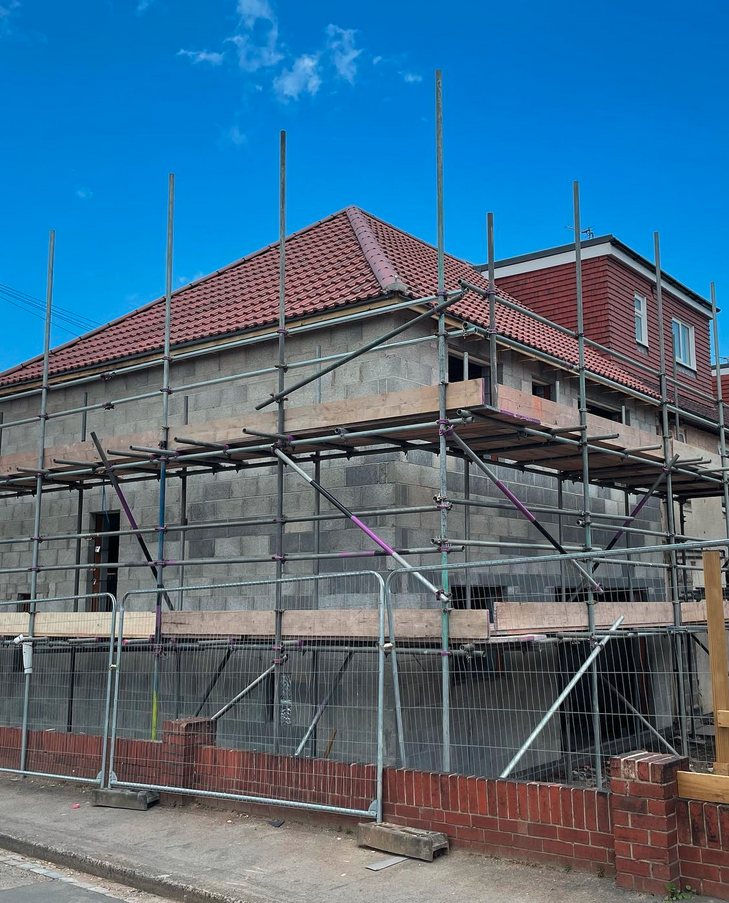 New build property with scaffolding around hipped tile roof