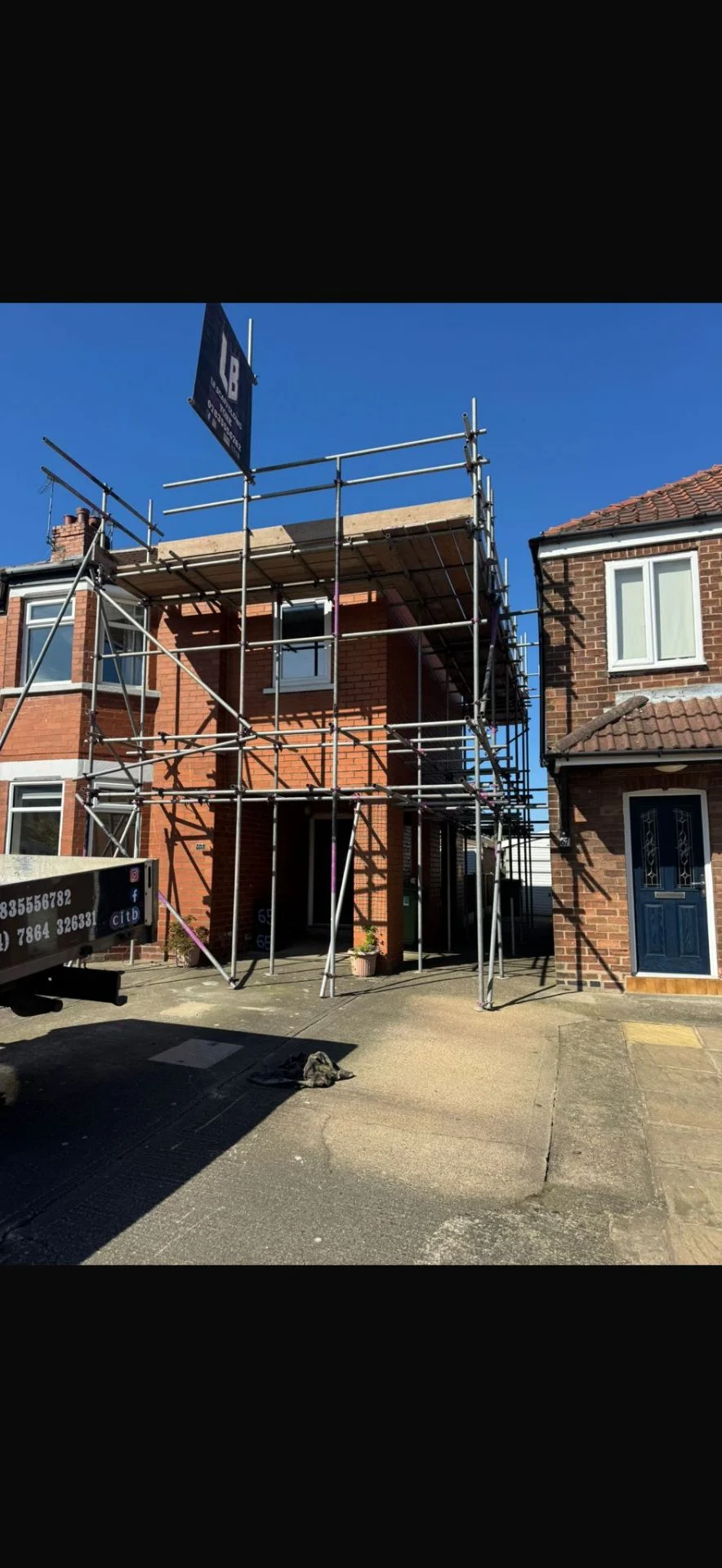Red-brick semi in York with full front-elevation scaffolding and LB Scaffolding Ltd banner