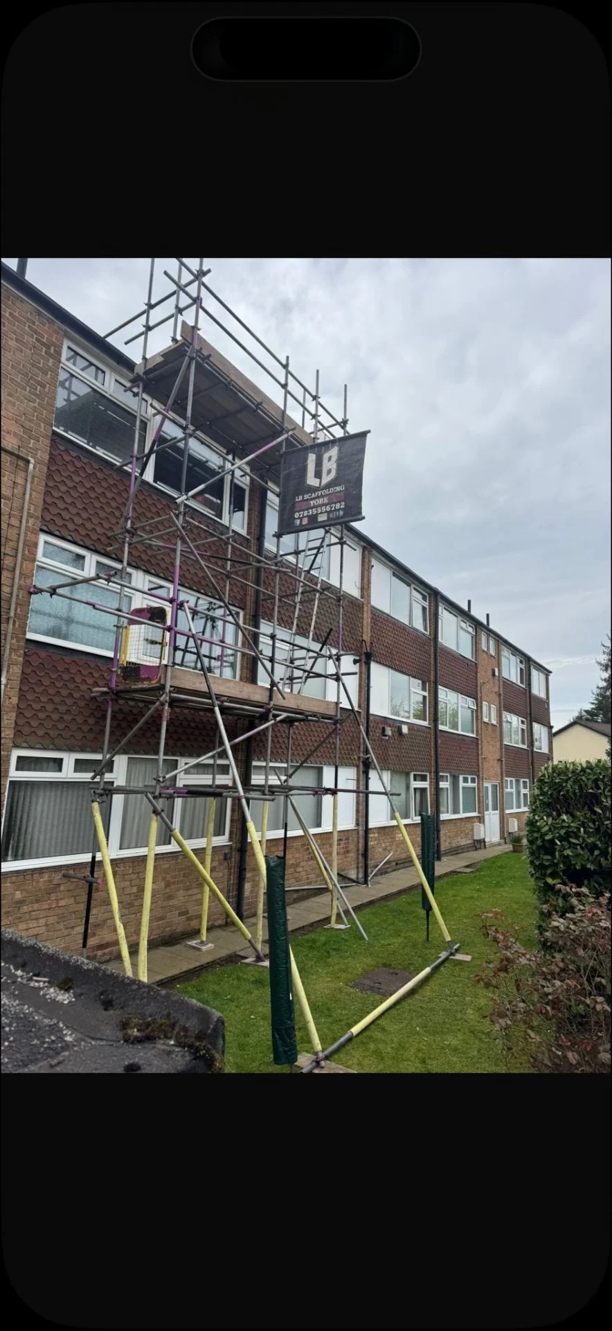 Three-storey block of flats with scaffold tower and LB Scaffolding Ltd banner to the front