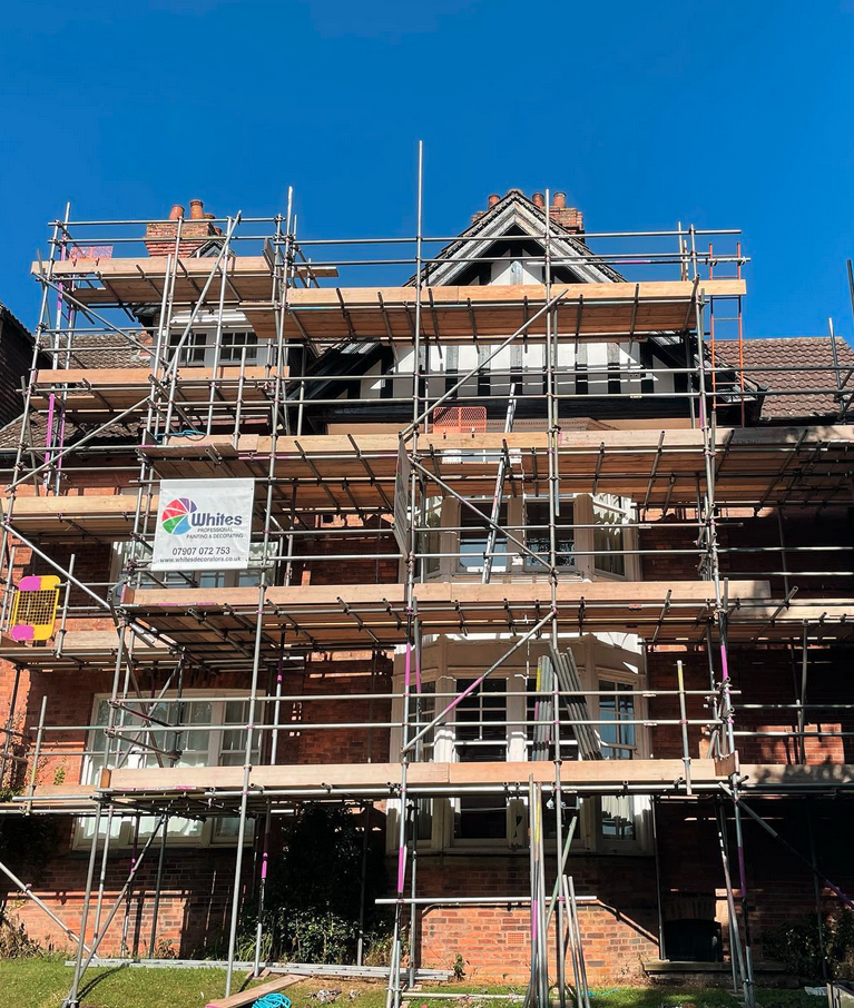 Tall red-brick property with full four-lift scaffolding for decorating